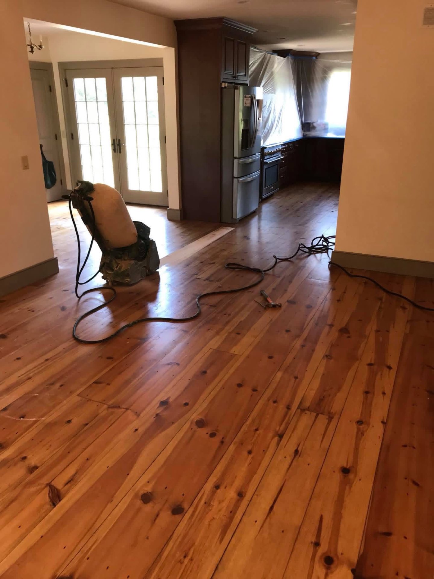 Drum sander at work on wide-plank pine floors in a Chicopee kitchen mid-refinish